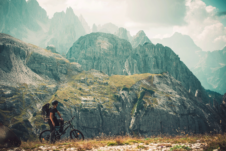 Man on trail biking holiday on mountain bike overlooking mountains
