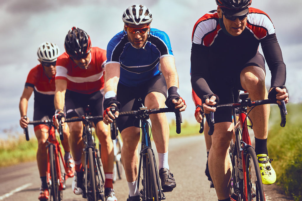 Cyclists racing on country roads on a sunny day in the UK.