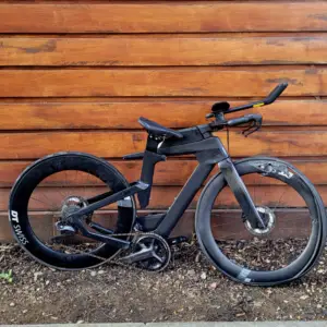 A heavily damaged time trial bike leaning against a wall after a crash.