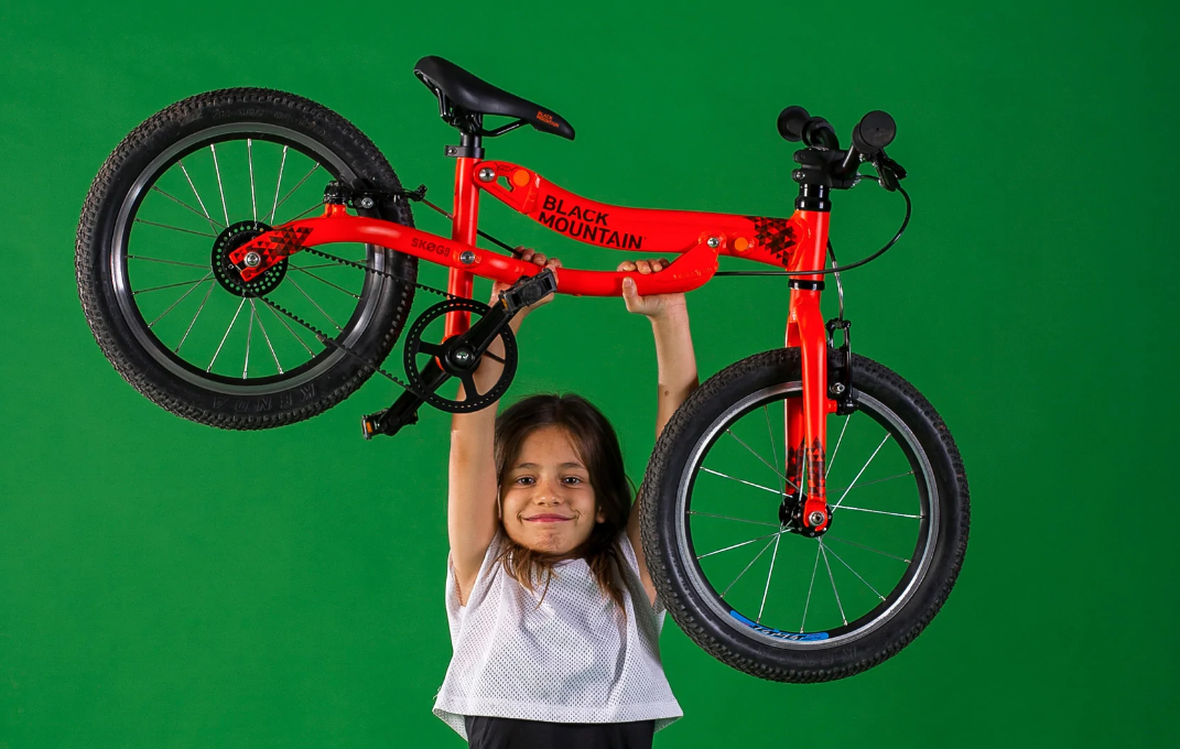 Young child holding their bicycle above their head