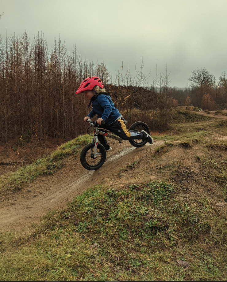 A boy on his balance bike riding over jumps