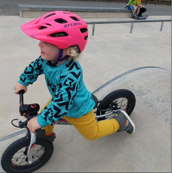 A boy on his balance bike riding over a ramp