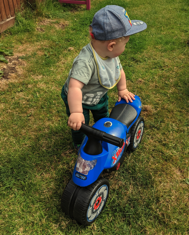 A toddler holding a plastic bike