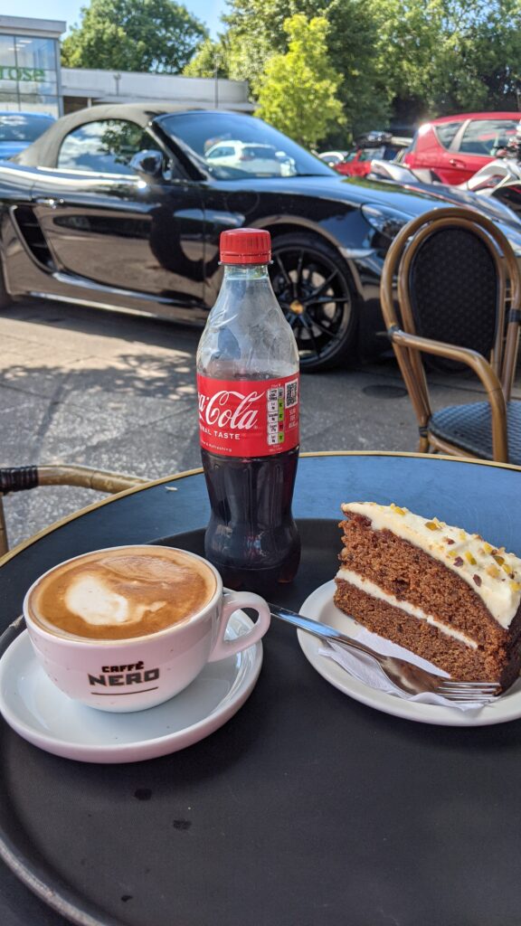 Coca cola, a cake and a coffee on a table outside a café 