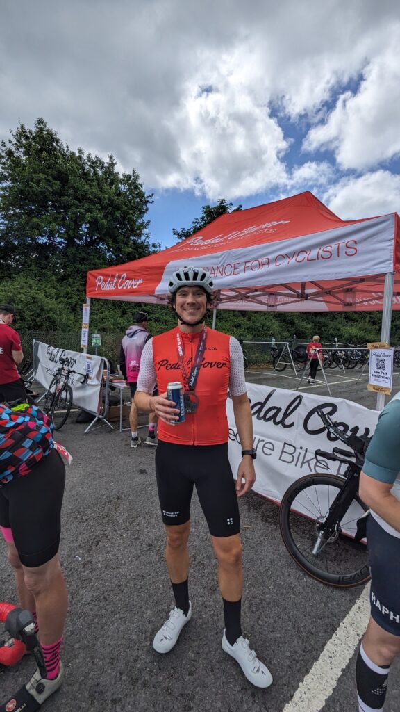 A cyclist holding a beer after completing a sportive ride