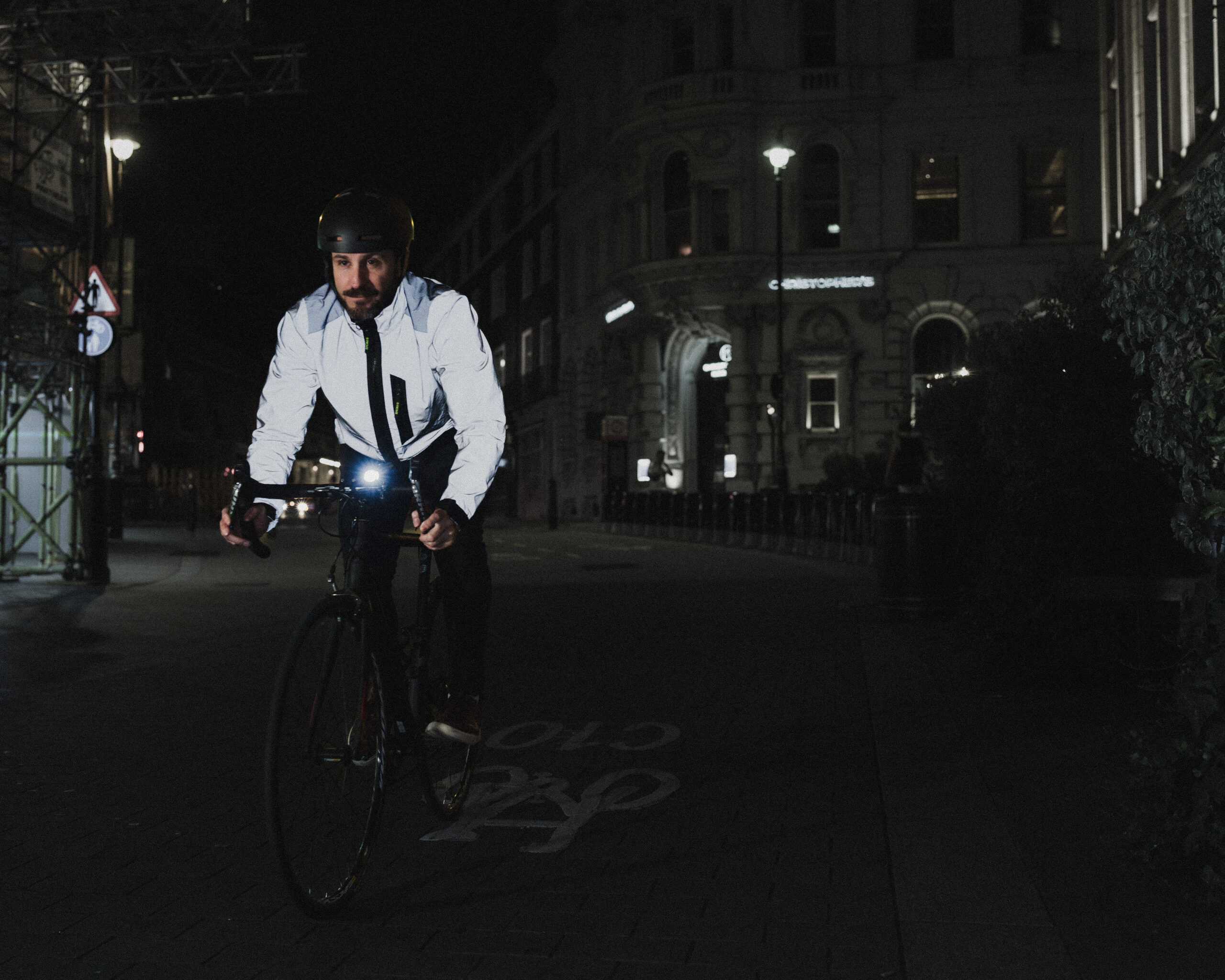 a cyclist riding at night wearing a reflective Proviz jacket